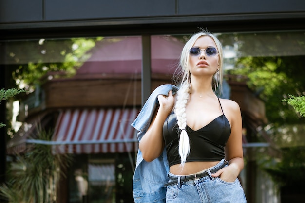 Beautiful sexy blonde woman posing outdoors in sunglasses in jeans