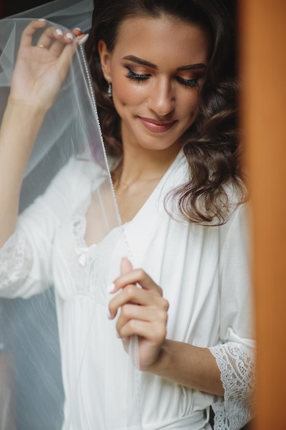 Beautiful sexy bride in white dress posing under curtain