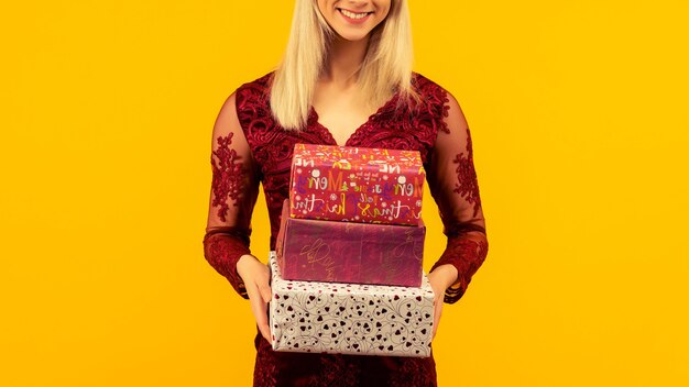 Una bella ragazza sexy con un cappello di capodanno e un vestito grigio, tiene in mano i regali. celebrazione di natale o capodanno