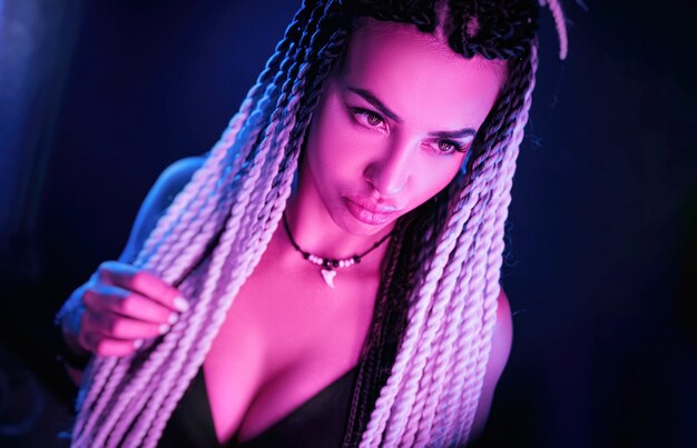 The beautiful sexy girl with long dreadlocks posing in neon light