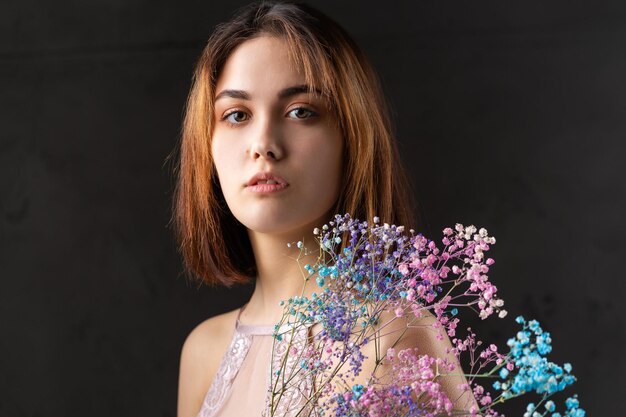 Красивая сексуальная дама в элегантном обнаженном боди держит в руках цветы Модный портрет красоты фотомодели девушки в студии
