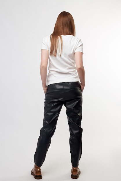Beautiful sexy pretty girl with long brown hair and perfect body weared in black leather pants and white shirt bronze puce hazel russet boots Isolated on white background