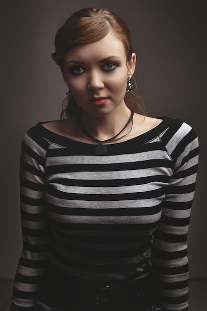 Beautiful sexy slim girl posing sitting on a black cube, in gray studio