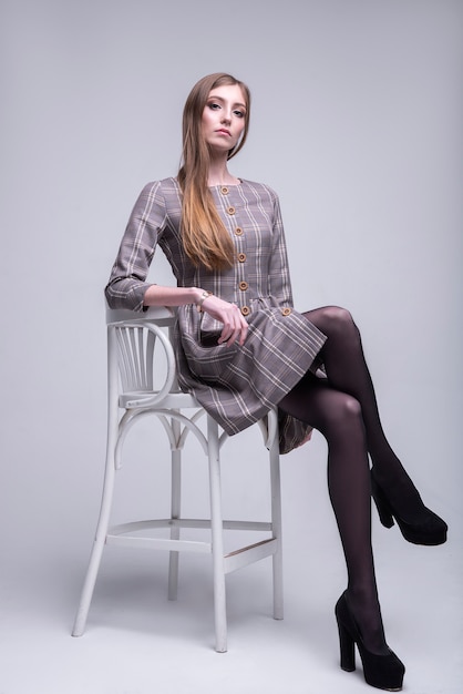 Beautiful sexy slim woman  sitting  on a high chair.