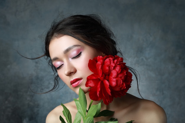 Beautiful sexy stylish young adult in elegant dress with nice bouquet of pink peonies. Studio retouched shot