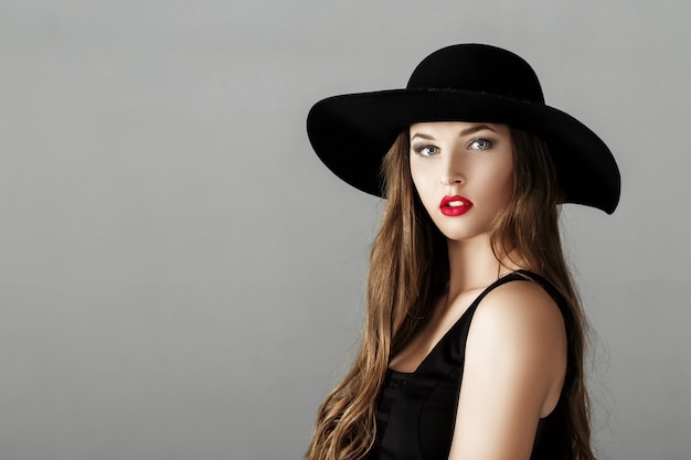 Beautiful sexy woman with red lipstick in a black hat