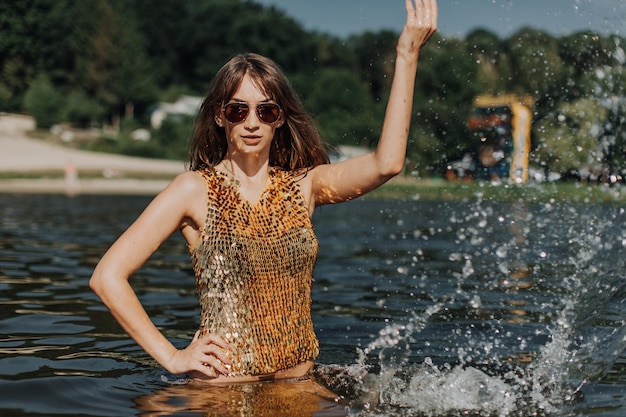 Beautiful sexy young girl with perfect slim figure with long hair and bathing suit in fashionable stylish sun glasses sitting on the steps of swimming pool swim sunbathe have fun at beach party