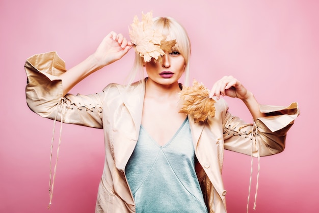 Beautiful sexy young woman lies on wood background. Attractive young woman in a seasonal clothes whith golden leaf.