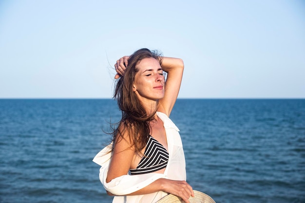 Beautiful sexy young woman with closed eyes on the background of the sea.