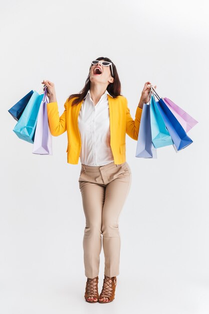 beautiful shocked young business woman posing isolated over white wall holding shopping bags.