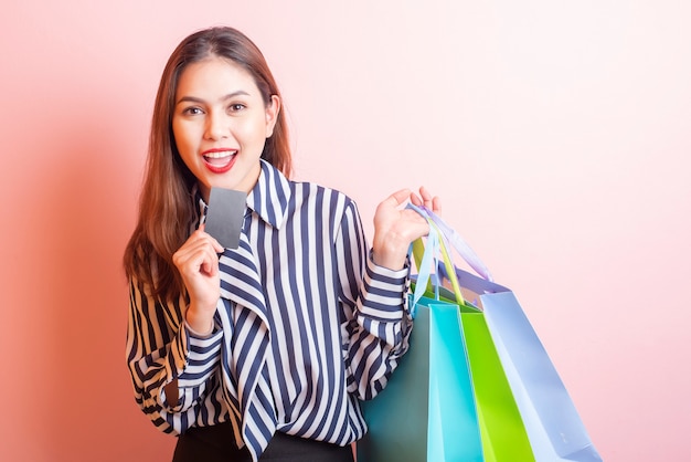 Beautiful shopping woman is smiling on pink  