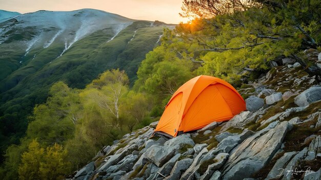 Beautiful shot of an orange tent on rocky mountain surrounded by trees during sunset