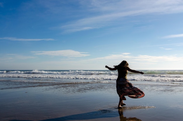 Beautiful shot of a woman dancing on the sea shore