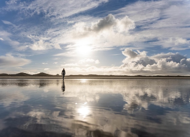 Beautiful shot of a woman walking across the beach at a calm lake