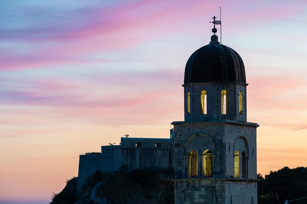 Beautiful silhouette of a church tower in Dubrovnik during sunset evening