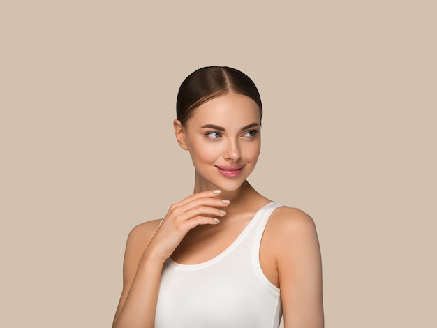 Beautiful skin face woman natural make up healthy skin touching her face. Color background. Brown