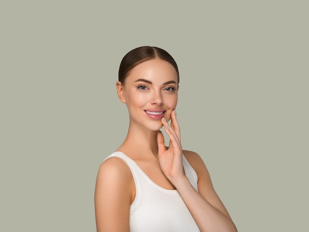 Beautiful skin face woman natural make up healthy skin touching her face. Color background. Green