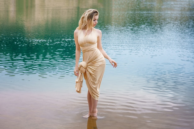 Beautiful slender girl with long hair posing standing in the water.