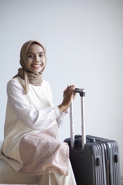 A Beautiful smailing Muslim Asian woman holding the suitcase looks at the camera