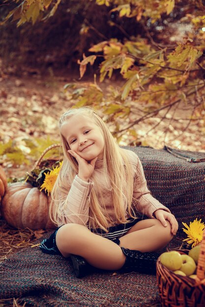 Beautiful small girl with cute and funny hedgehog baby in autumn nature