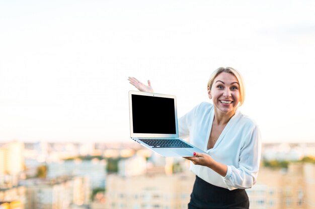 Beautiful smart business lady stand on the roof with laptop in hands, show empty laptop