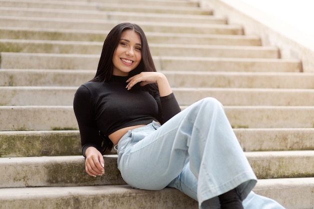 コンクリートの階段に座っているラティーナ女性の美しい笑顔
