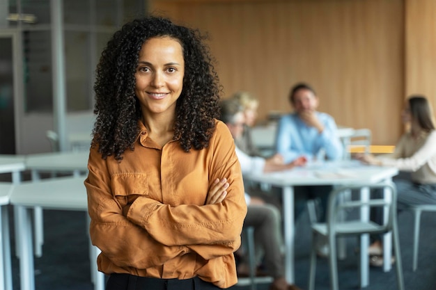 beautiful smiling african american businesswoman manager worker holding arms crossed in office