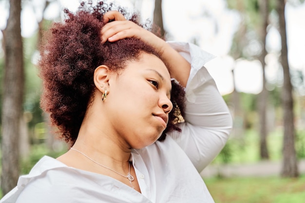 彼女の巻き毛のヘアスタイルに触れる美しい笑顔のアフリカ系アメリカ人女性