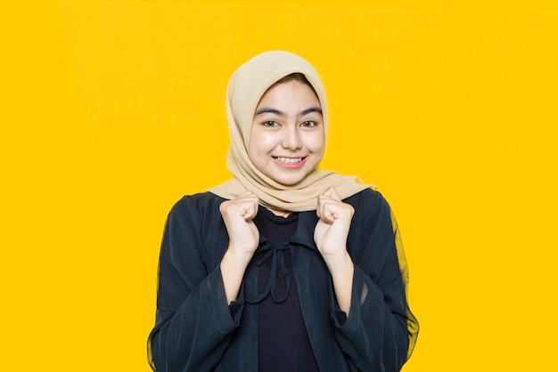 Beautiful smiling Asian woman pointing hand to empty space on yellow wall