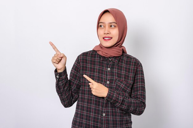 Photo beautiful smiling asian woman wearing hijab pointing with finger isolated on white background