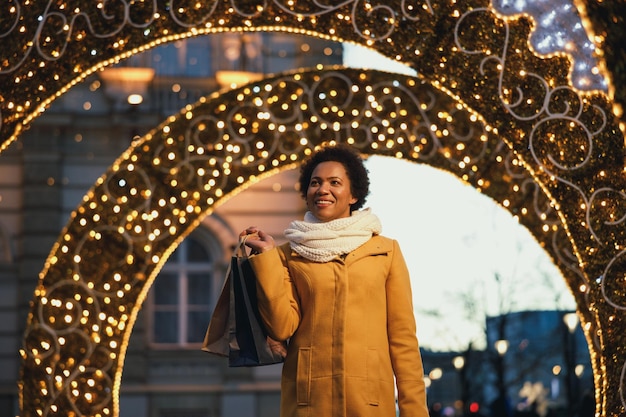 Beautiful smiling black woman walking and shopping during Christmas holidays in the city.