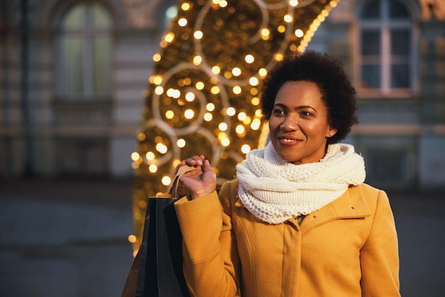 Beautiful smiling black woman walking and shopping during xmas\
holidays in the city.