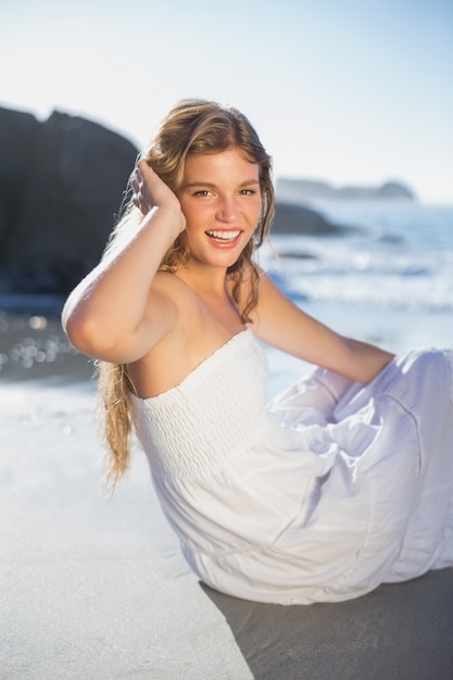 해변에 앉아 sundress에 아름 다운 미소 금발