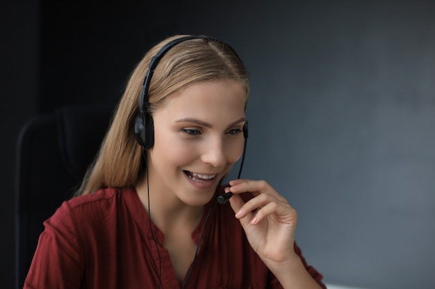 Beautiful smiling call center worker in headphones is working isolated over grey background.