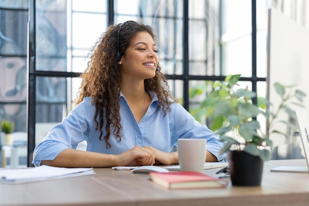 Beautiful smiling call center worker in headphones is working at modern office