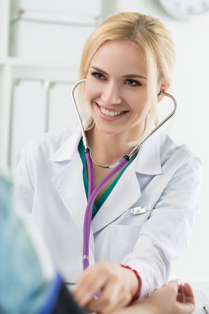 Beautiful smiling cheerful female medicine doctor measuring blood pressure to patient. Medical and healthcare concept