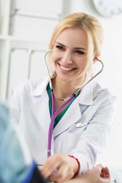 환자에 게 혈압을 측정하는 아름 다운 미소 명랑 한 여성 의학 의사. 의료 및 건강 관리 개념