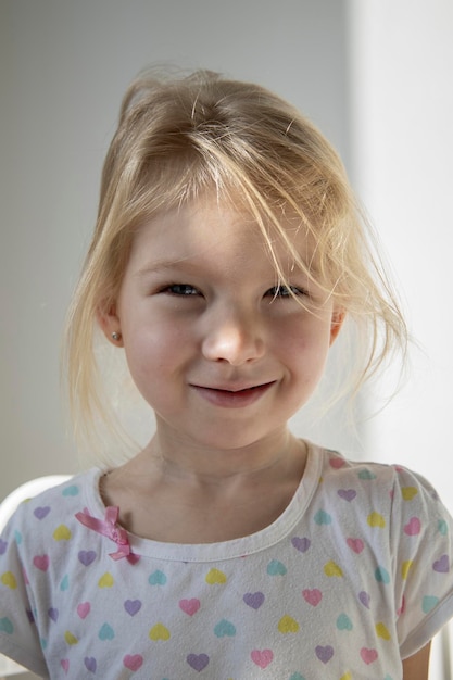 Beautiful smiling child girl blonde on the background of a white wall