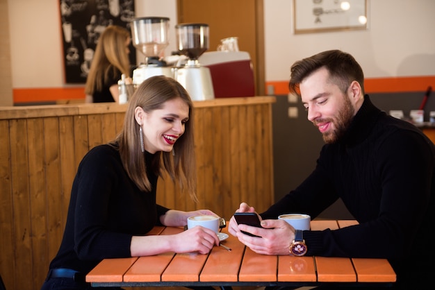 Beautiful Smiling Couple In Cafe Using Phone