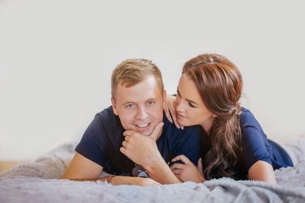 Beautiful smiling couple hugging and lying on the bed at home