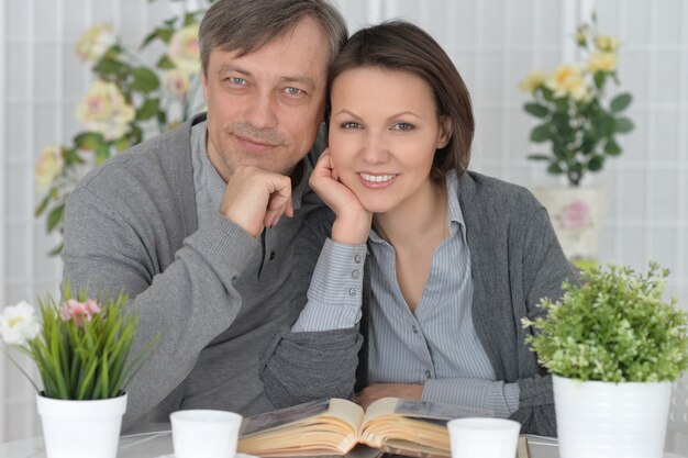 Beautiful smiling couple sitting at table reading a book