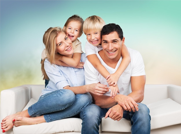 Beautiful smiling family sitting at sofa on background