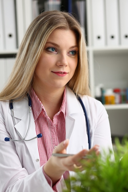 Beautiful smiling female doctor sit at workplace