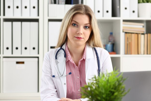 Beautiful smiling female doctor sit at workplace