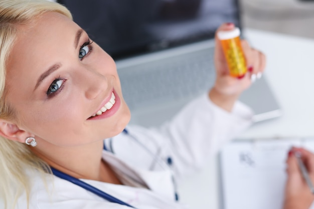 Beautiful smiling female doctor write prescription