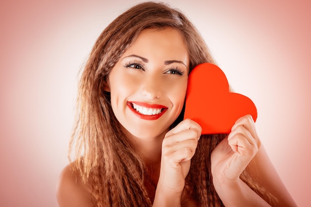 Beautiful smiling girl holding a red heart.