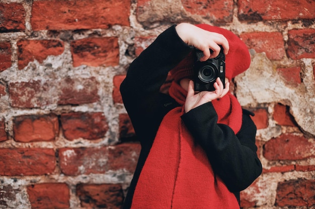 赤いベレー帽とスカーフの美しい笑顔の女の子は、街の通りで写真を撮ります。高品質の写真