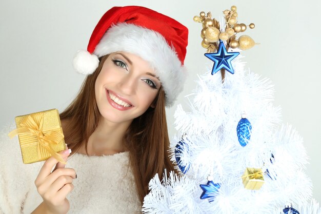 Beautiful smiling girl near Christmas tree with gift