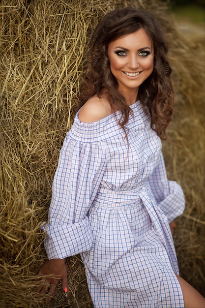 Beautiful smiling girl near a hay bale in the countryside