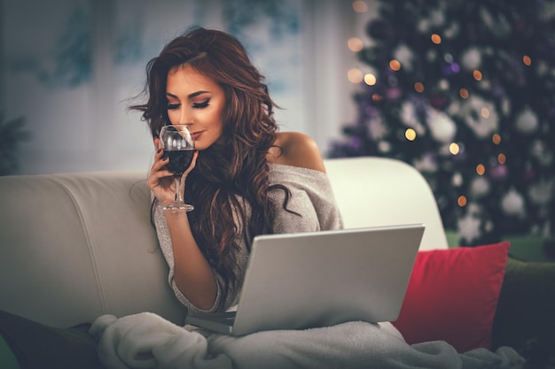 Beautiful smiling girl relaxing in bed with gingerbread cookie and glass of black vine.